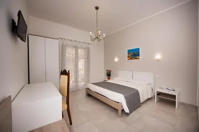 a white bedroom with two beds and a television at Casa Mariú in Castellammare del Golfo