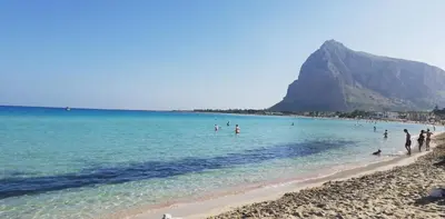 a group of people on a beach with a mountain in the background at Casa Mariú in Castellammare del Golfo