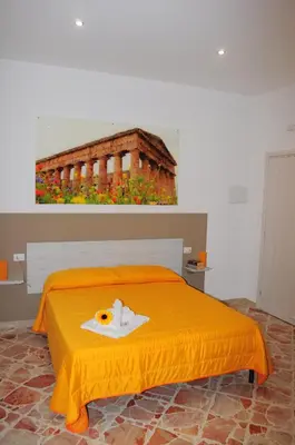 a bed with an orange bedspread and a picture of a building at I Paesaggi in Castellammare del Golfo