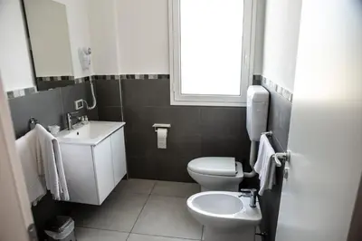 a bathroom with a sink and a toilet and a window at Piano Monaco in Carini