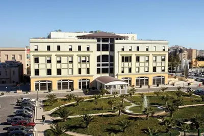 a large yellow building with cars parked in a parking lot at Al Civico 8 - Palermo in Palermo