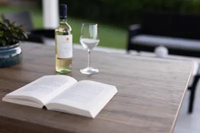 an open book and a glass of wine on a wooden table at Villa Cristina - Relax - Piscina e Vista Mare in Castellammare del Golfo