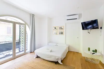 a white room with a bed and a tv at Central Mezzanine in Palermo