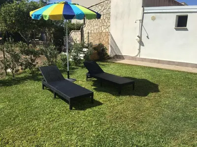 two chairs and an umbrella on the grass at Villa dei Limoni sul Mare in Castellammare del Golfo
