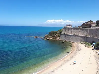 a beach in front of a wall and the ocean at Villa Verde in Alcamo