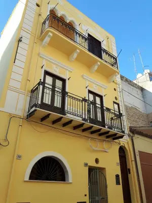 a yellow building with a balcony on it at Casa Vacanze Mannina in Castellammare del Golfo