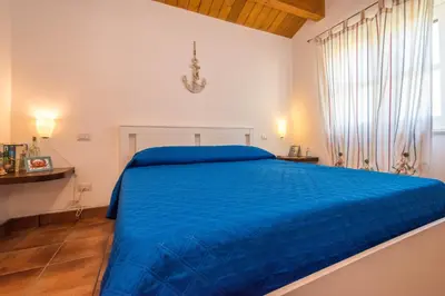 a large blue bed in a white bedroom at Casa del Sale, a 50 m dalla spiaggia in Lascari