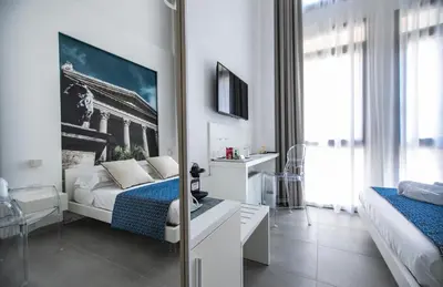 a bedroom with a bed and a desk and a tv at Suite Quaroni in Palermo