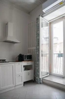 a kitchen with white cabinets and a large window at Ai Mori in Palermo