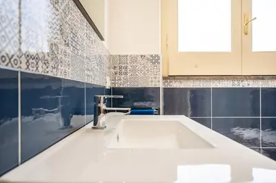 a white sink in a bathroom with blue tiles at Le Casette Di Maria Pia in Mondello