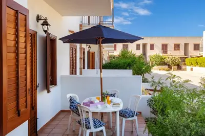 a table and chairs with an umbrella on a patio at Residence Smeraldo in San Vito lo Capo