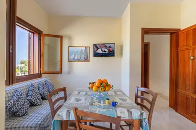 a dining room with a table and a couch at Residence Smeraldo in San Vito lo Capo