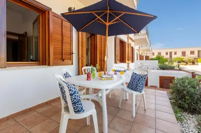 a white table with chairs and an umbrella on a patio at Residence Smeraldo in San Vito lo Capo