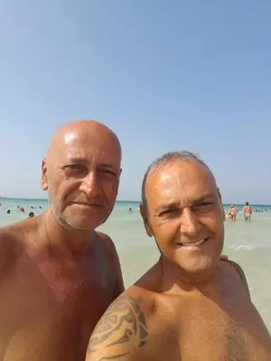 two men posing for a picture on the beach at DE MEO Guest House in Castellammare del Golfo