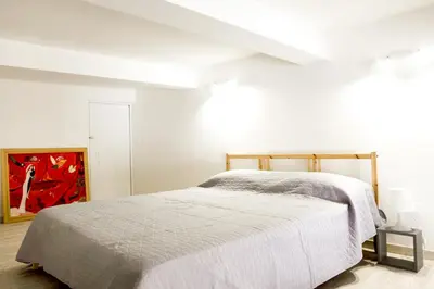 a white bedroom with a bed and a painting at 90100 in Palermo