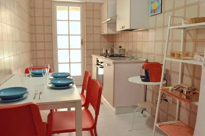 a kitchen with a table with red chairs and a table and a kitchen with at Casa DahLia Mondello in Mondello