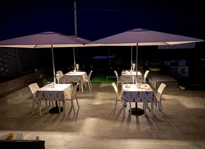 three tables with purple umbrellas on a patio at night at Castello di Sabbia in Trabia