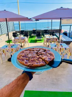 a pizza sitting on a blue plate on a table at Castello di Sabbia in Trabia
