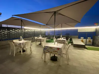 a patio with tables and chairs under a large umbrella at Castello di Sabbia in Trabia