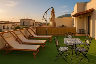 a patio with chairs and a table and an umbrella at Appartamenti Penelope in Mondello