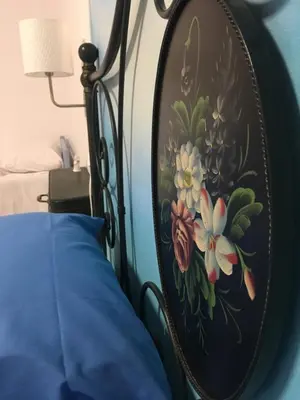 a painting of flowers on a wall next to a bed at Alter Ego in Lascari