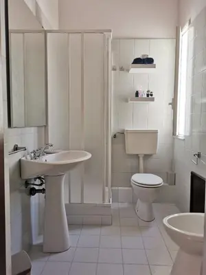 a white bathroom with a toilet and a sink at Alter Ego in Lascari