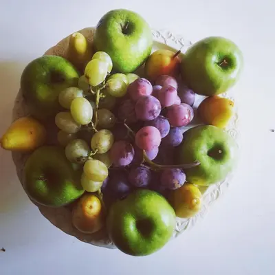 a bowl of grapes and apples and other fruits at La stanza di Angi a Mondello in Palermo
