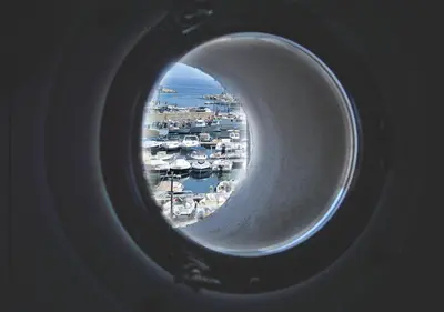 a view of a harbor through a round window at Case Vacanza Calamaro in Trabia