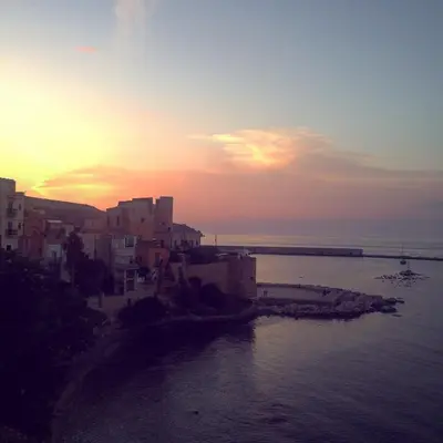a sunset over a city and the water with buildings at Mizzika Vacanze in Castellammare del Golfo