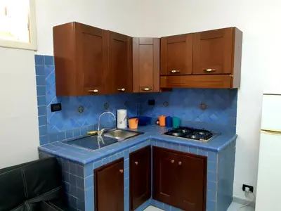 a kitchen with a blue tile counter top and wooden cabinets at Appartamenti Cavarretta Seminterrati in Mondello