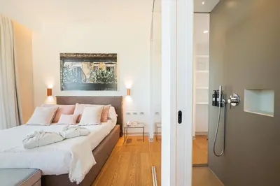 a bedroom with a bed with white sheets and pink pillows at Unìco Boutique Hotel d'Arte in Mondello