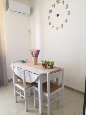 a white table with chairs and a clock on the wall at Cappuccini Green Relax in Carini