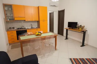 a kitchen with orange cabinets and a table with a bowl of fruit on it at Casa Benzo in Palermo