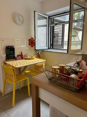 a kitchen with a table and yellow chairs and a table and a clock at Like Home Palermo in Palermo