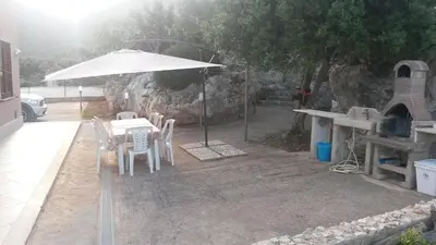 a table and chairs with an umbrella and a oven at Villa Cloe in San Vito lo Capo