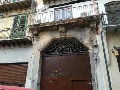 a building with a large brown door and a balcony at Casa in palazzo Graffeo Sven in Palermo