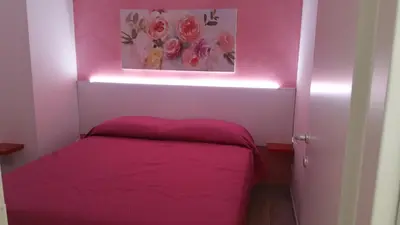 a small bedroom with a bed in a pink room at CASA VACANZE DEL GOLFO 2 in Castellammare del Golfo