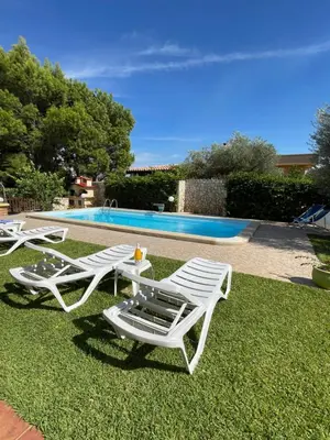 two white lounge chairs and a table and a pool at Villino Giulia in Altavilla Milicia