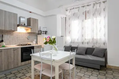 a kitchen and living room with a white table and chairs at Il Tarì Apartment in Palermo