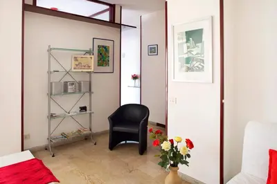 a living room with a black chair and a vase of flowers at Suite Vera in Palermo