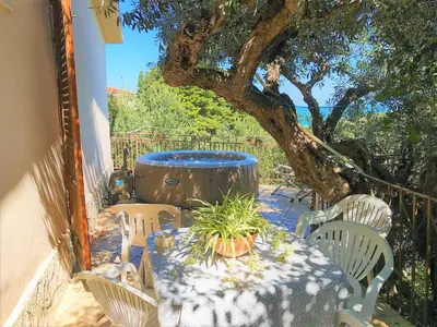 a table and chairs with a tree and a barrel at Guidaloca Bay House con mini-piscina Scopello in Castellammare del Golfo
