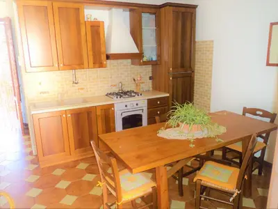 a kitchen with a wooden table and a dining room at Guidaloca Bay House con mini-piscina Scopello in Castellammare del Golfo