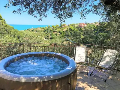 a large hot tub sitting next to two chairs at Guidaloca Bay House con mini-piscina Scopello in Castellammare del Golfo