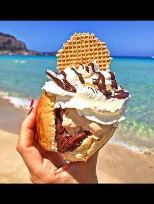 a person holding a waffle sandwich with whipped cream and chocolate at Mondello's Pearl in Mondello