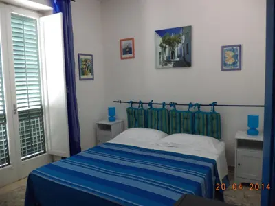 a bedroom with a blue and white bed and a window at La Caletta in Santa Flavia