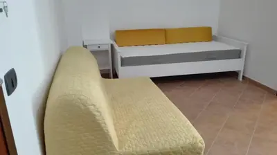 a room with two beds and a couch in a room at Casavacanze corallo in Isola delle Femmine