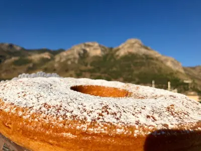 a pastry with powdered sugar on it with mountains in the background at COCCIU D’AMURI in Castellammare del Golfo