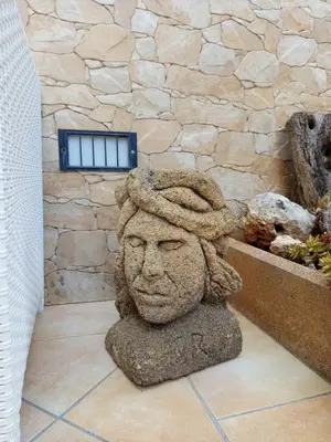 a statue of a head in front of a stone wall at Amaryllis Hotel in San Vito lo Capo