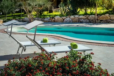 a row of lounge chairs next to a swimming pool at Villa Thyrrenia in Castellammare del Golfo