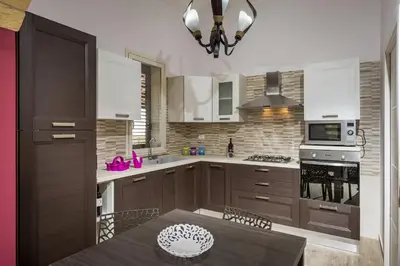 a kitchen with wooden cabinets and a table with a dining room at Villa Gea in Castellammare del Golfo